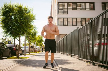 Yakışıklı seksi erkek vücut geliştirmeci sporcu adam çıplak gövde, kentsel avlularında bulunan açık hava çalıştırmak sabah ile