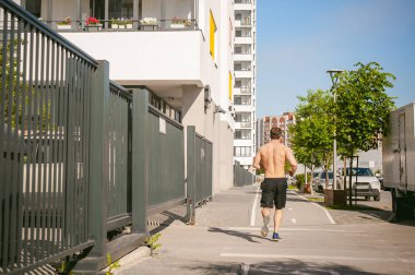 Yakışıklı seksi erkek vücut geliştirmeci sporcu adam çıplak gövde, kentsel avlularında bulunan açık hava çalıştırmak sabah ile