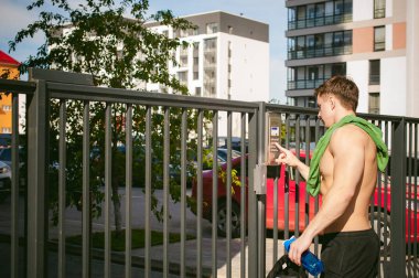 Yakışıklı seksi erkek atlet adam çıplak gövde ile sahanın geçidin yakınlarında, kapıyı açmak için dahili telefon arama