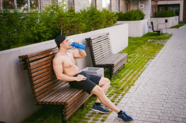 Çıplak gövde evin avlusunda bir bankta eğitim içecekler su bir şişe sonra bir erken güneşli yaz sabahı dinlenme adamla yakışıklı seksi erkek atlet