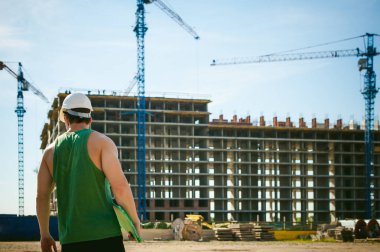 Genç seksi erkek vücut geliştirmeci atlet. Müdür mühendis Oluşturucu koruyucu kask yapı ve inşaat İnşaat arka plan üzerinde duran beyaz belgeleri ile el vinç