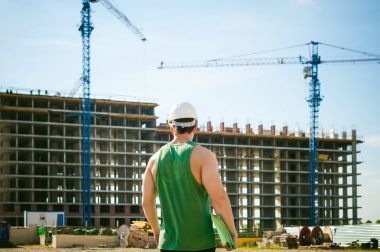 Genç seksi erkek vücut geliştirmeci atlet. Müdür mühendis Oluşturucu koruyucu kask yapı ve inşaat İnşaat arka plan üzerinde duran beyaz belgeleri ile el vinç