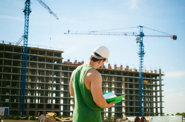 Genç seksi erkek vücut geliştirmeci atlet. Müdür mühendis Oluşturucu koruyucu kask yapı ve inşaat İnşaat arka plan üzerinde duran beyaz belgeleri ile el vinç