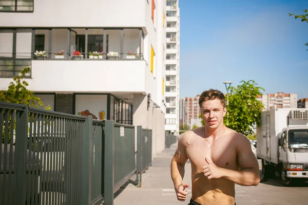 Schöner sexy männlicher Bodybuilder Athlet mit nacktem Oberkörper, Morgenlauf unter freiem Himmel in städtischen Höfen — Stockfoto