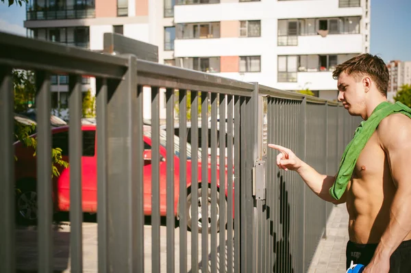 Schöner sexy männlicher Athlet Mann mit nacktem Oberkörper, steht in der Nähe des Tores und ruft Gegensprechanlage, um Tür zu öffnen — Stockfoto