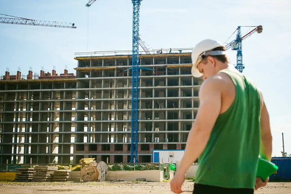 Genç seksi erkek vücut geliştirmeci atlet. Müdür mühendis Oluşturucu koruyucu kask yapı ve inşaat İnşaat arka plan üzerinde duran beyaz belgeleri ile el vinç