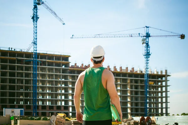 Genç seksi erkek vücut geliştirmeci atlet. Müdür mühendis Oluşturucu koruyucu kask yapı ve inşaat İnşaat arka plan üzerinde duran beyaz belgeleri ile el vinç