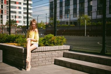 Genç güzel kadın açık havada bahçede yeşil ve evler, sıcak yaz güneşli gün zemin karşı gezinme