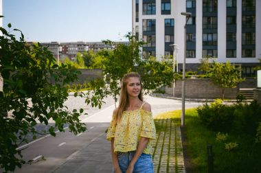 Genç güzel kadın açık havada bahçede yeşil ve evler, sıcak yaz güneşli gün zemin karşı gezinme