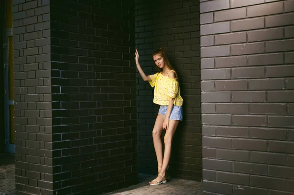 Nagyon aranyos fiatal nő pózol a falnak fekete tégla — Stock Fotó