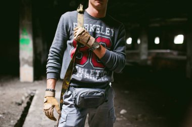 Elinde bir karabina tabanca ile atletik adam gri elbise. Yakın çekim silah ile taktik eldiven