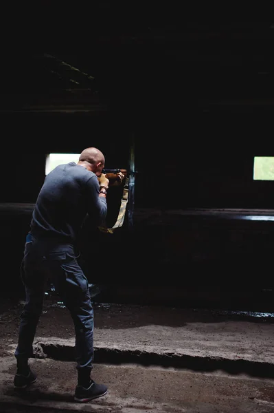 Atletik adamla elinde bir karabina silah gri kıyafetler — Stok fotoğraf