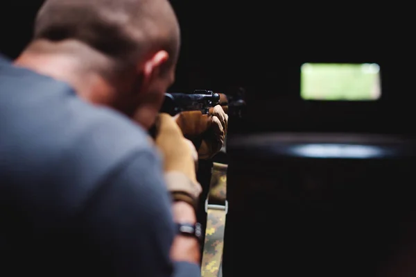 Uomo atletico in abiti grigi con una pistola di carabina in mano — Foto Stock