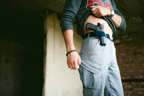 Joven atlético sosteniendo un arma detrás de su cinturón . —  Fotos de Stock