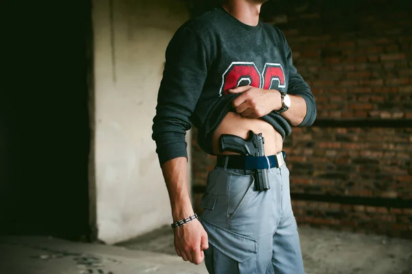 Joven atlético sosteniendo un arma detrás de su cinturón . — Foto de Stock