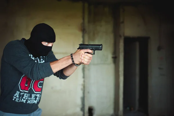 Lekkoatletycznego mężczyzna w mieście balaclava, kryje w sobie pistolet w ręku, jest zagrożona ze strzelaniem, mające — Zdjęcie stockowe