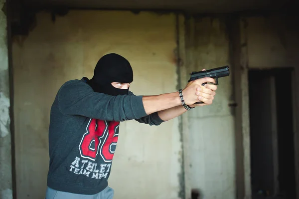 Lekkoatletycznego mężczyzna w mieście balaclava, kryje w sobie pistolet w ręku, jest zagrożona ze strzelaniem, mające — Zdjęcie stockowe