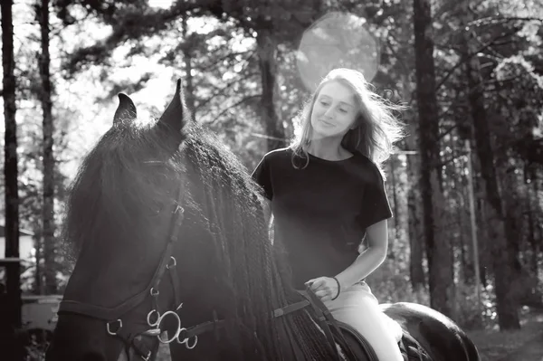 Retrato emocional de una jinete mujer, a horcajadas, enamorada de caballos, semental frisón negro pura raza mascota, al aire libre — Foto de Stock