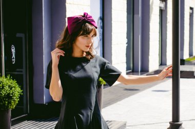 Karanlık bir şık elbiseli güzel kadın butikler yakınındaki cadde boyunca elini kolunu sallaya dönüyor. Bir moda kız portresi