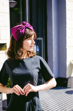 Karanlık bir şık elbiseli güzel kadın butikler yakınındaki cadde boyunca elini kolunu sallaya dönüyor. Bir moda kız portresi