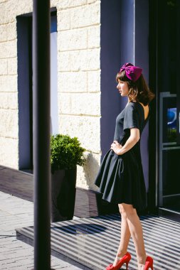 Karanlık bir şık elbiseli güzel kadın butikler yakınındaki cadde boyunca elini kolunu sallaya dönüyor. Bir moda kız portresi