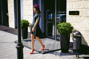 Karanlık bir şık elbiseli güzel kadın butikler yakınındaki cadde boyunca elini kolunu sallaya dönüyor. Bir moda kız portresi