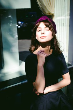 Karanlık bir şık elbiseli güzel kadın butikler yakınındaki cadde boyunca elini kolunu sallaya dönüyor. Bir moda kız portresi