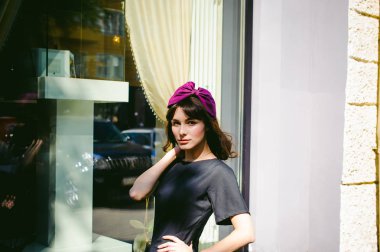 Karanlık bir şık elbiseli güzel kadın butikler yakınındaki cadde boyunca elini kolunu sallaya dönüyor. Bir moda kız portresi