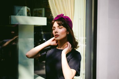 Karanlık bir şık elbiseli güzel kadın butikler yakınındaki cadde boyunca elini kolunu sallaya dönüyor. Bir moda kız portresi