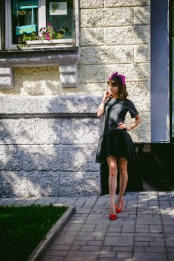 Karanlık bir şık elbiseli güzel kadın butikler yakınındaki cadde boyunca elini kolunu sallaya dönüyor. Bir moda kız portresi