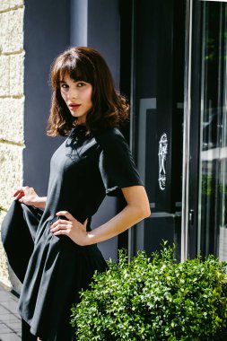 Karanlık bir şık elbiseli güzel kadın butikler yakınındaki cadde boyunca elini kolunu sallaya dönüyor. Bir moda kız portresi