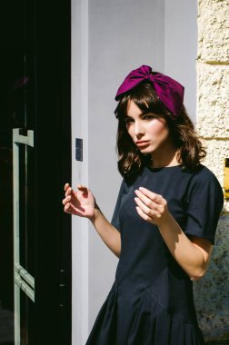 Karanlık bir şık elbiseli güzel kadın butikler yakınındaki cadde boyunca elini kolunu sallaya dönüyor. Bir moda kız portresi