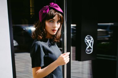 Karanlık bir şık elbiseli güzel kadın butikler yakınındaki cadde boyunca elini kolunu sallaya dönüyor. Bir moda kız portresi