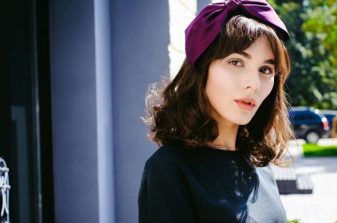 Karanlık bir şık elbiseli güzel kadın butikler yakınındaki cadde boyunca elini kolunu sallaya dönüyor. Bir moda kız portresi