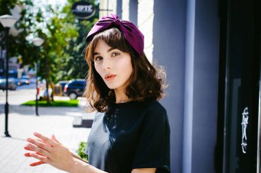 Karanlık bir şık elbiseli güzel kadın butikler yakınındaki cadde boyunca elini kolunu sallaya dönüyor. Bir moda kız portresi