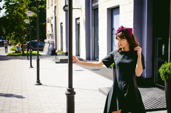 Karanlık bir şık elbiseli güzel kadın butikler yakınındaki cadde boyunca elini kolunu sallaya dönüyor. Bir moda kız portresi