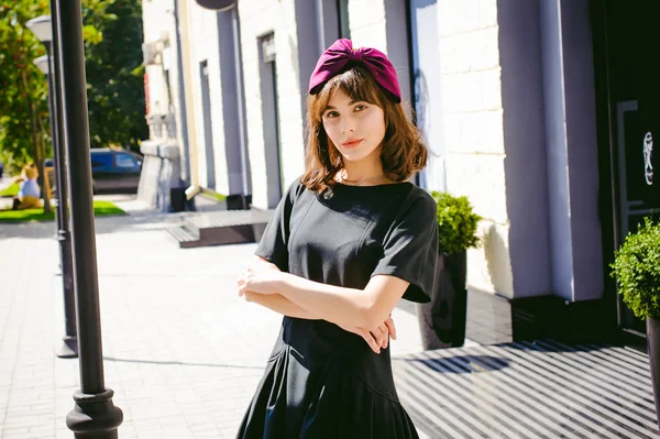 Karanlık bir şık elbiseli güzel kadın butikler yakınındaki cadde boyunca elini kolunu sallaya dönüyor. Bir moda kız portresi