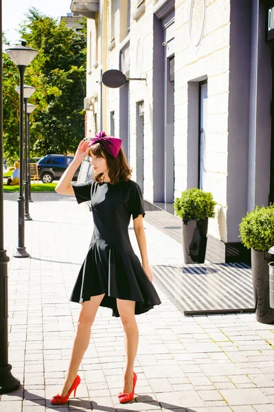 Beautiful woman in a dark stylish dress strolls along the street, near boutiques. Portrait of a fashionable girl — Stock Photo, Image