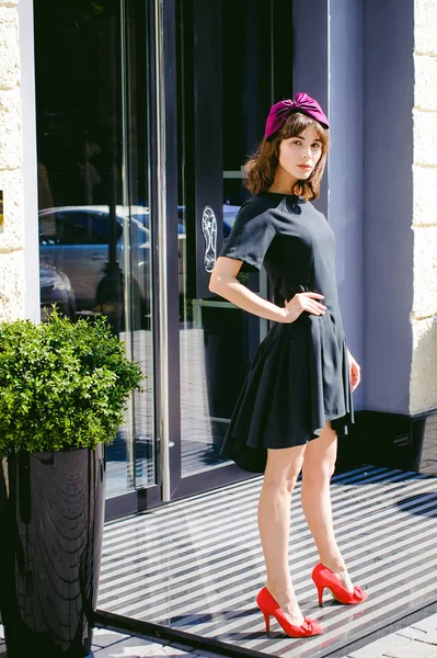 Karanlık bir şık elbiseli güzel kadın butikler yakınındaki cadde boyunca elini kolunu sallaya dönüyor. Bir moda kız portresi