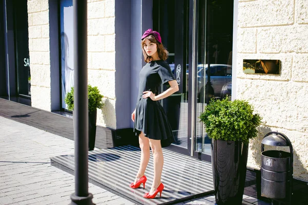 Hermosa mujer en un vestido elegante oscuro pasea por la calle, cerca de las boutiques. Retrato de una chica de moda — Foto de Stock