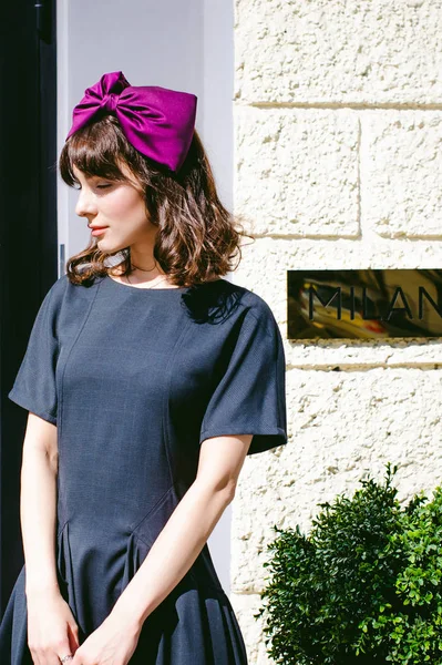 Karanlık bir şık elbiseli güzel kadın butikler yakınındaki cadde boyunca elini kolunu sallaya dönüyor. Bir moda kız portresi