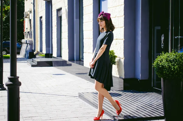 Belle femme dans une robe sombre et élégante se promène le long de la rue, près des boutiques. Portrait d'une fille à la mode — Photo