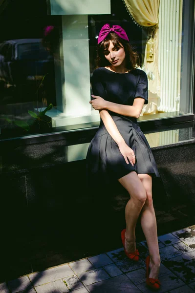 Hermosa mujer en un vestido elegante oscuro pasea por la calle, cerca de las boutiques. Retrato de una chica de moda — Foto de Stock