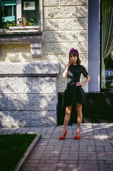 Karanlık bir şık elbiseli güzel kadın butikler yakınındaki cadde boyunca elini kolunu sallaya dönüyor. Bir moda kız portresi