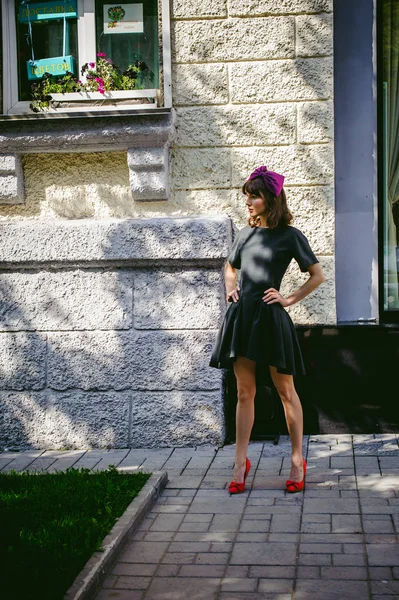 Mooie vrouw in een donkere stijlvolle jurk wandelingen langs de straat, in de buurt van boetieks. Portret van een modieus meisje — Stockfoto