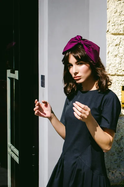 Karanlık bir şık elbiseli güzel kadın butikler yakınındaki cadde boyunca elini kolunu sallaya dönüyor. Bir moda kız portresi