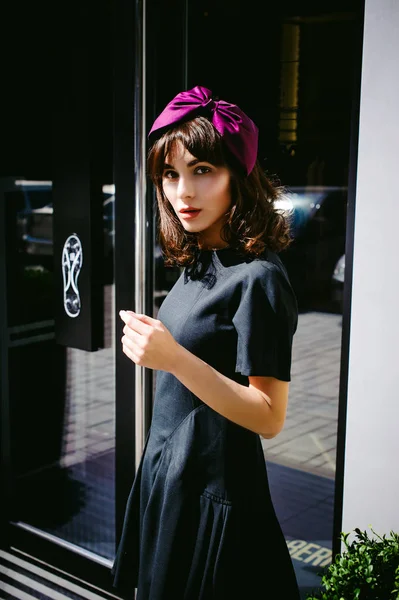 Karanlık bir şık elbiseli güzel kadın butikler yakınındaki cadde boyunca elini kolunu sallaya dönüyor. Bir moda kız portresi