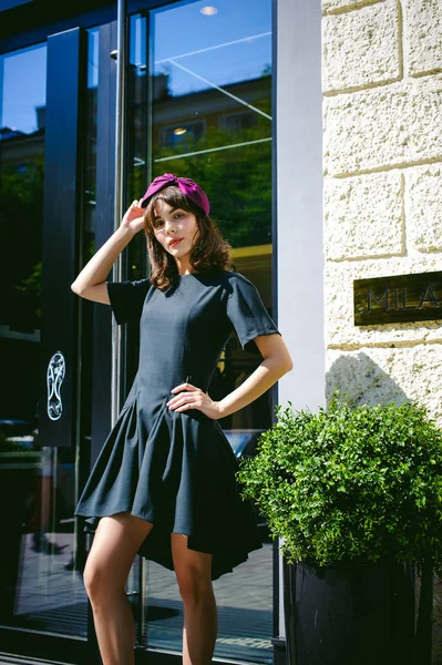 Karanlık bir şık elbiseli güzel kadın butikler yakınındaki cadde boyunca elini kolunu sallaya dönüyor. Bir moda kız portresi