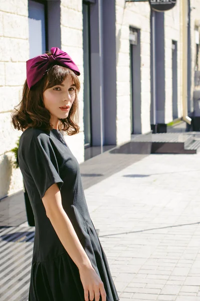 Karanlık bir şık elbiseli güzel kadın butikler yakınındaki cadde boyunca elini kolunu sallaya dönüyor. Bir moda kız portresi