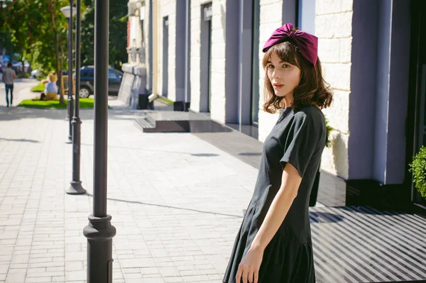 Karanlık bir şık elbiseli güzel kadın butikler yakınındaki cadde boyunca elini kolunu sallaya dönüyor. Bir moda kız portresi